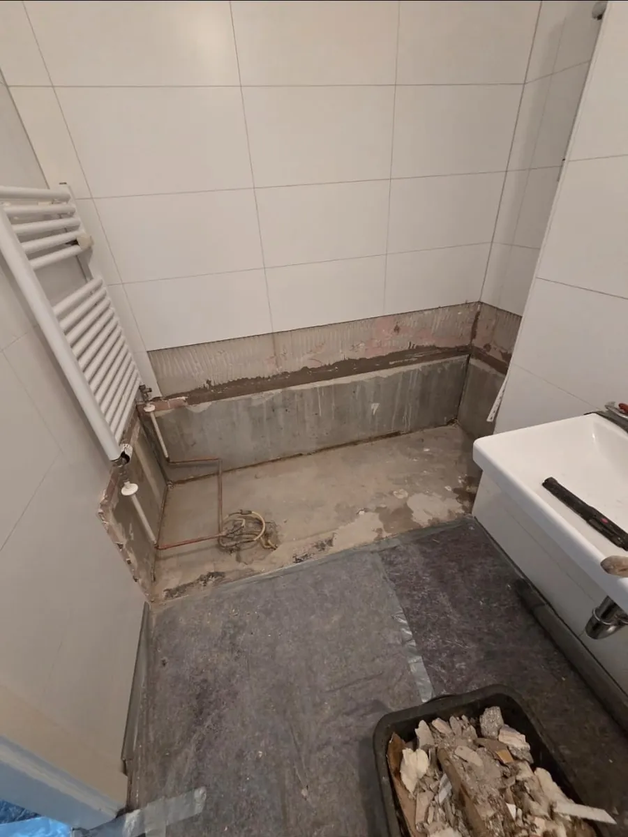 Badezimmer während der Sanierung: alte Duschwanne entfernt, Rohleitungen freigelegt